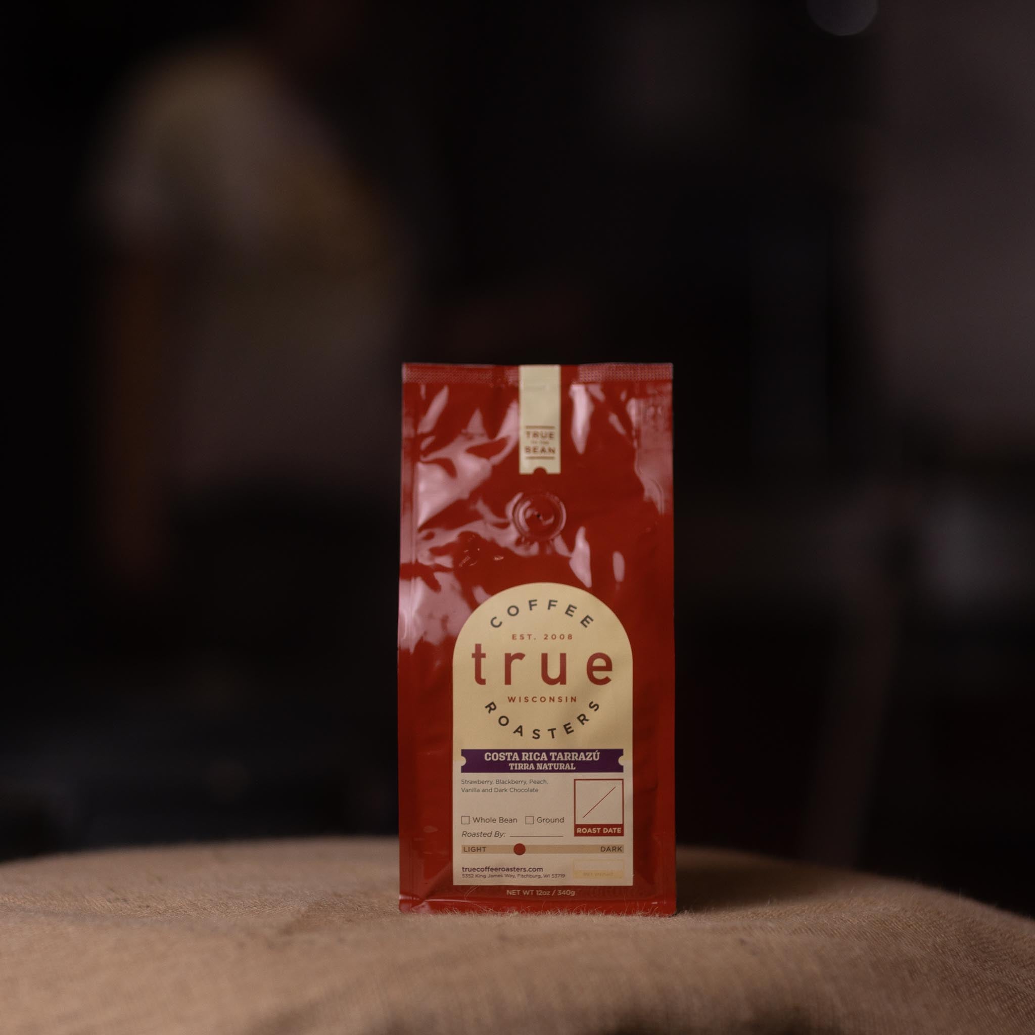 Red coffee bag with 'true roasters' label on a dark background